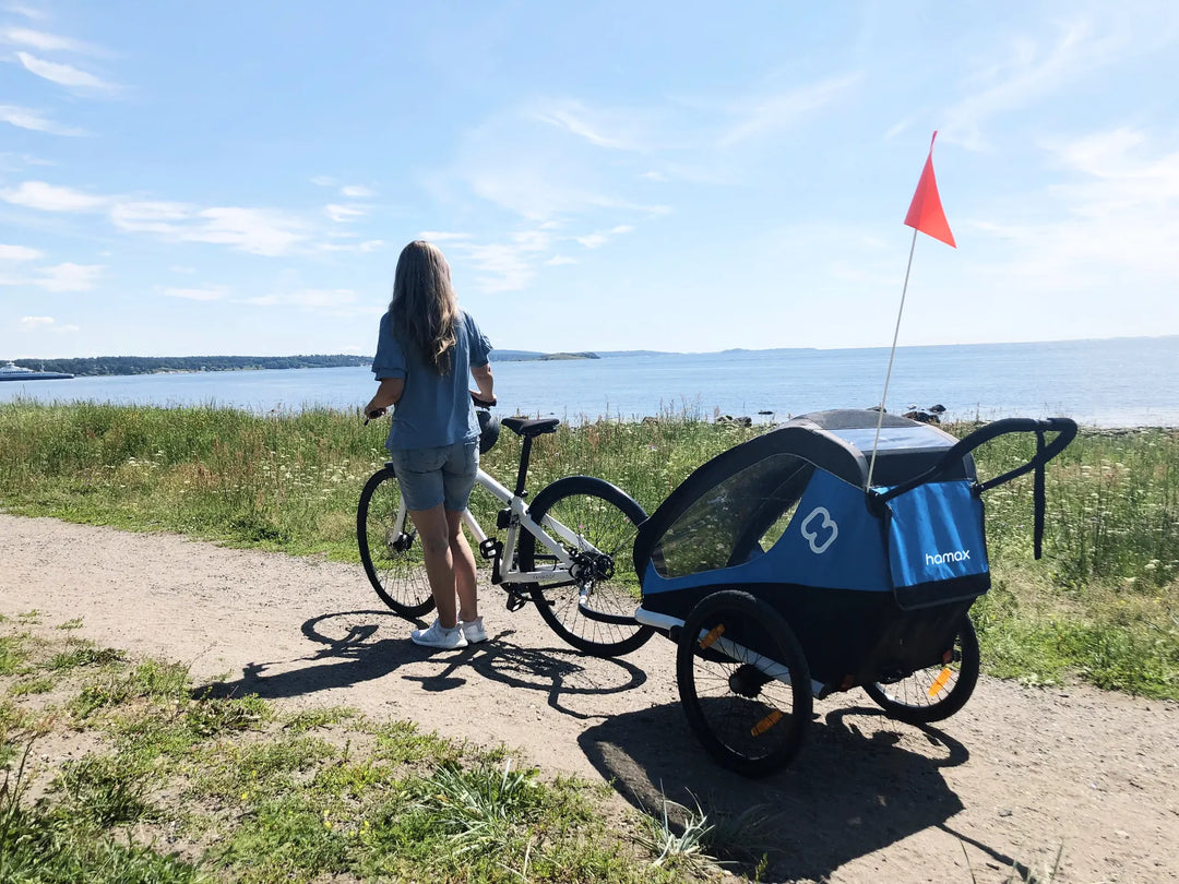 Hamax Traveller bike trailer attached to a bike near the water