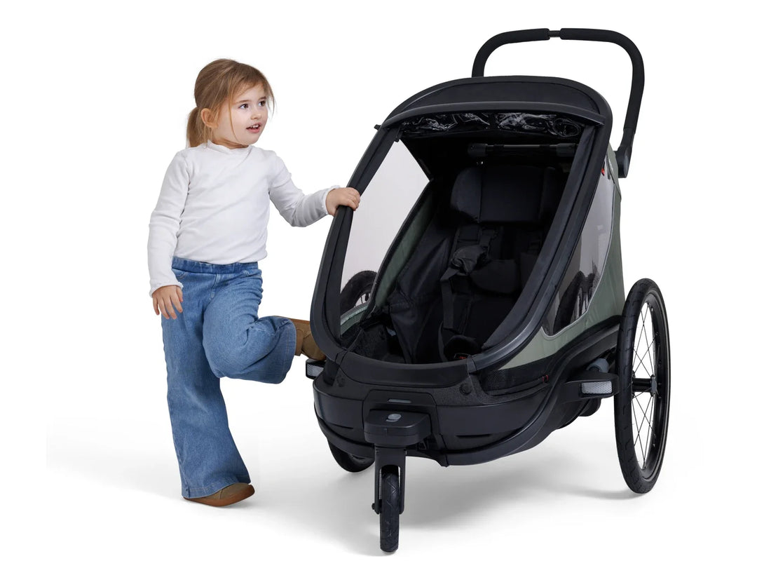 Hamax Outback Next One trailer with child beside the cabin
