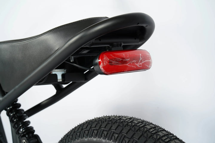 Close-up of a black bicycle seat with a red light on a white background